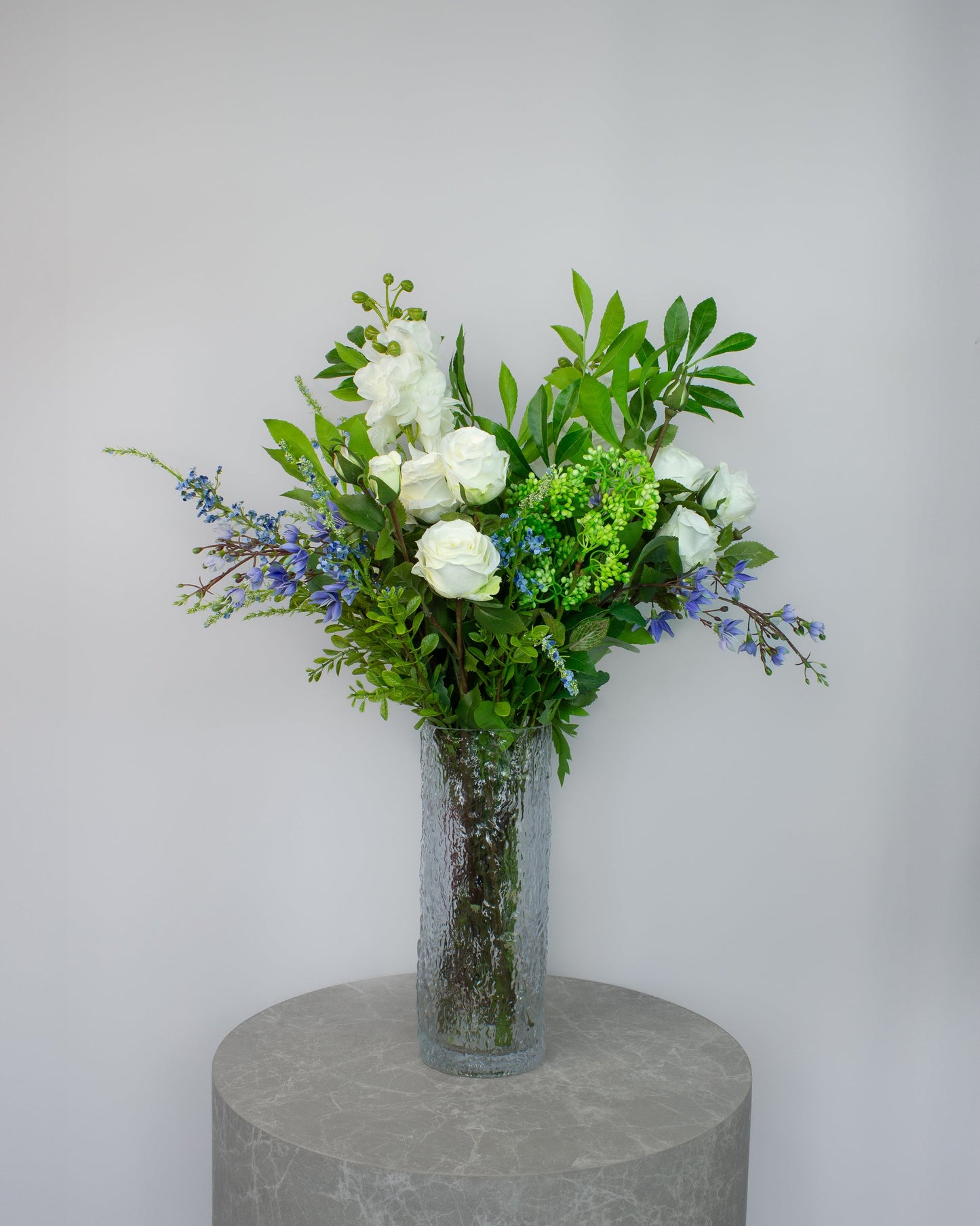 Blue Meadow naturtro kunstig buket med blå jasminblomster, hvide roser, riddersporer og lysegrøn hortensia i glasvase