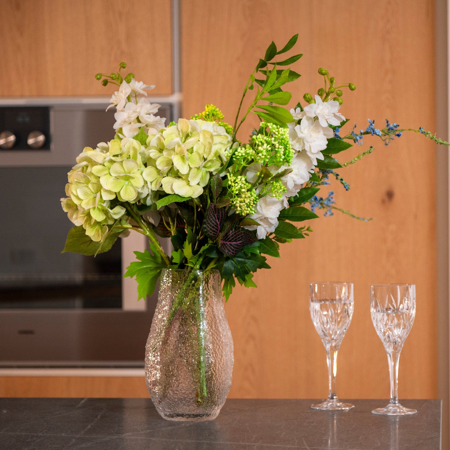 Forest Breeze buket i hvid vase som centerpiece på bord – grønne og hvide nuancer