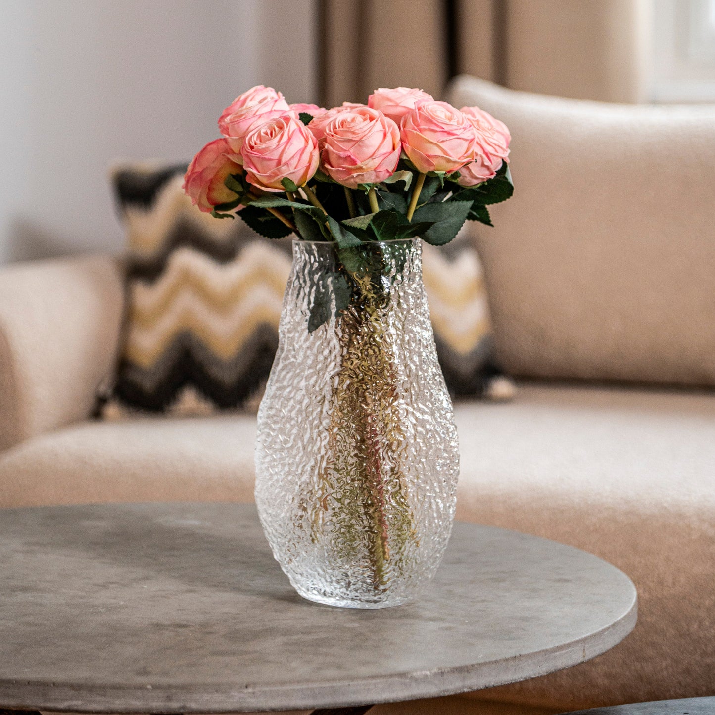 Buket af små, elegante roser i relief-glasvase på sofabord