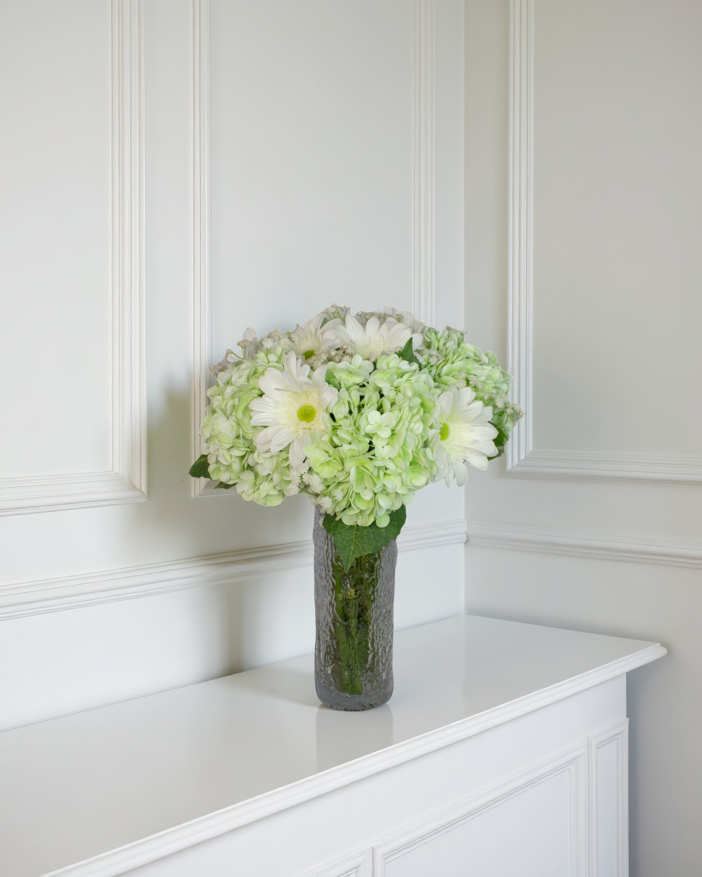 Daisy Cloud naturtro kunstig buket i grøn og hvid i høj glasvase på hvid konsol