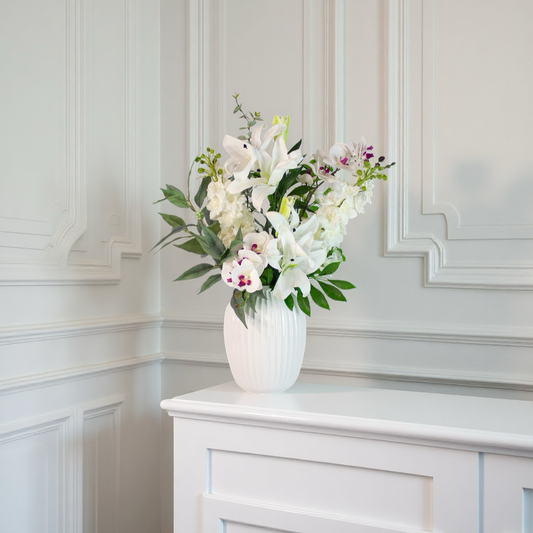 white serenity – kunstig hvid blomsterbuket i riflet vase på lys baggrund