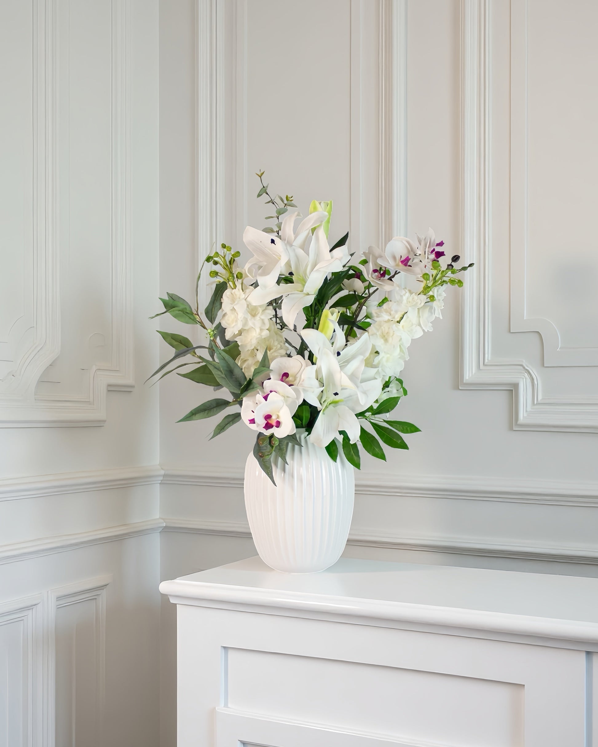 white serenity – kunstig hvid blomsterbuket i riflet vase på lys baggrund